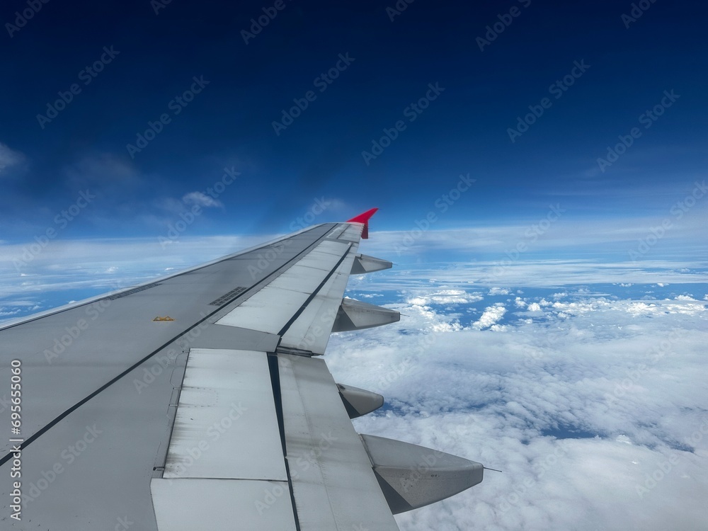 Airplane right side window view with plane wing and clouds