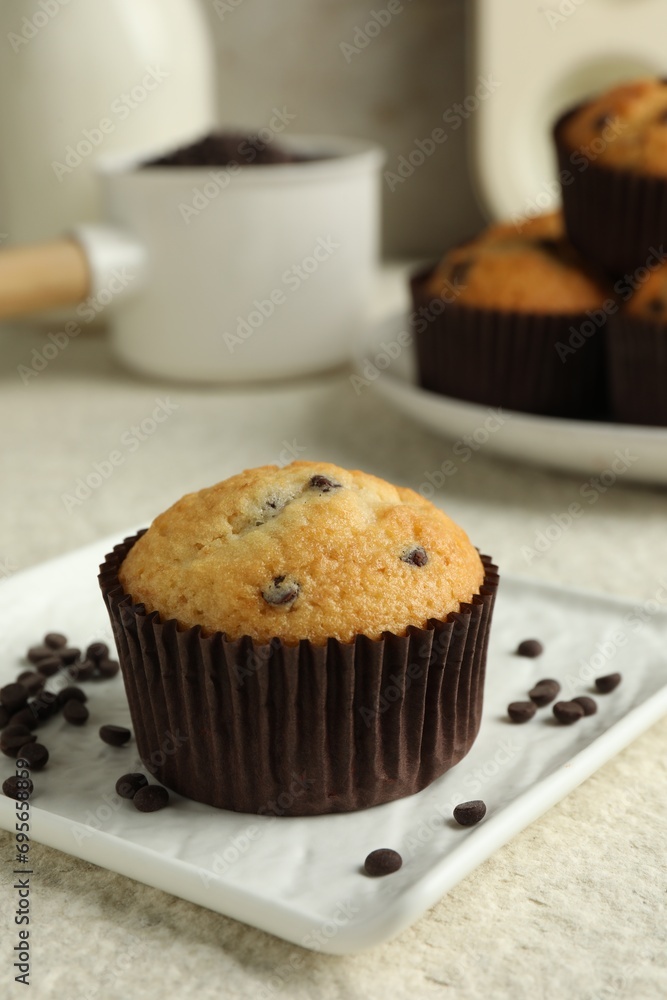 Delicious sweet muffin with chocolate chips on light textured table, closeup