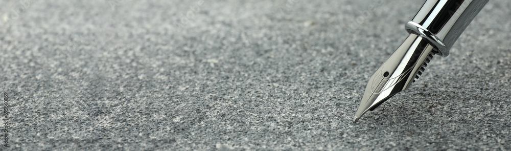 Fountain pen on grey textured table, closeup. Banner design with space for text