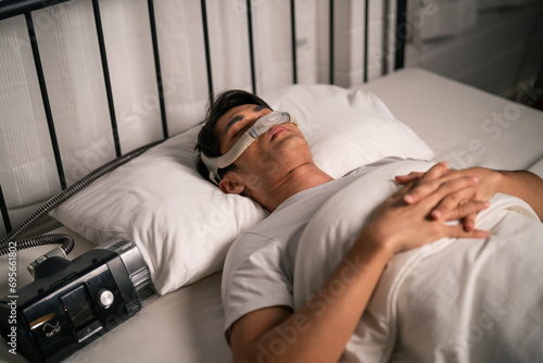 Asian man wearing cpap machine sleeping smoothly all night in bedroom.  photo