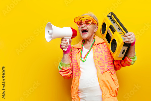 funny crazy old granny with tape recorder in sports hipster clothes listens to rock music and announces into megaphone