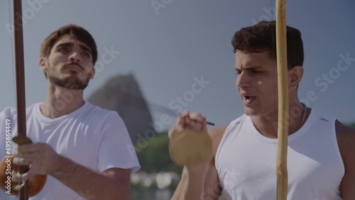 Jovens tocando instrumentos musicais tipicos brasileiros. Jogando capoeira, arte marcial afro-brasileira, no Rio de Janeiro. Cinematico 4k. photo
