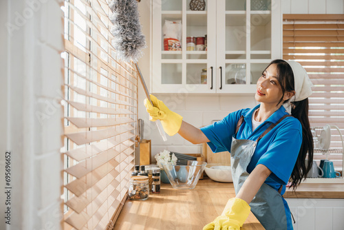 Woman enjoys cleaning dirty window blinds ensuring hygiene. Holding duster and whisk for routine housework. Modern cleaning for a clean home is portrayed. whisk photo