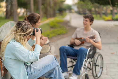 Woman taking a photo of a disabled friend playing music © Guillermo Spelucin