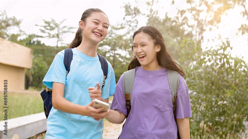 Happy Asian student girls walking and using smart phone in school