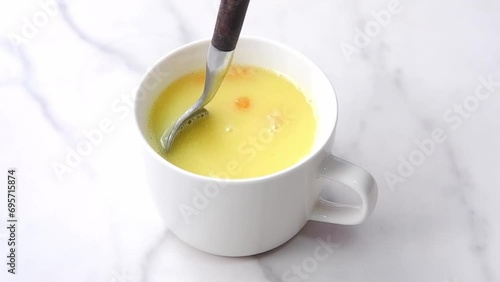 Stirring creamy corn potage with a spoon
