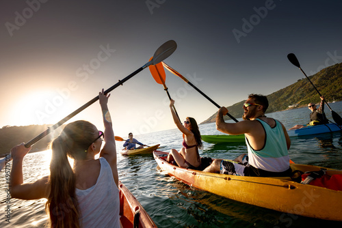 Big group of happy young friends are having fun and kayaking at sunset sea photo