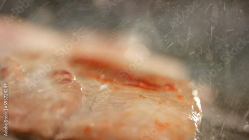 뜨거운 불판에 삼겹살을 굽자 기름이 튀고 육즙이 흐르는 클로즈업 영상  photo