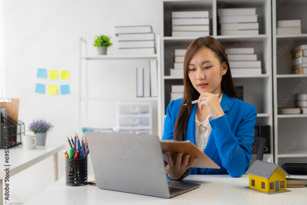 Home sales concept, real estate, Asian female employee with small house on table Along with the lease of the sales agreement related to the mortgage loan and home insurance offers. Home sales concept, real estate, Asian female employee with small house on table Along with the lease of the sales agreement related to the mortgage loan and home insurance offers.