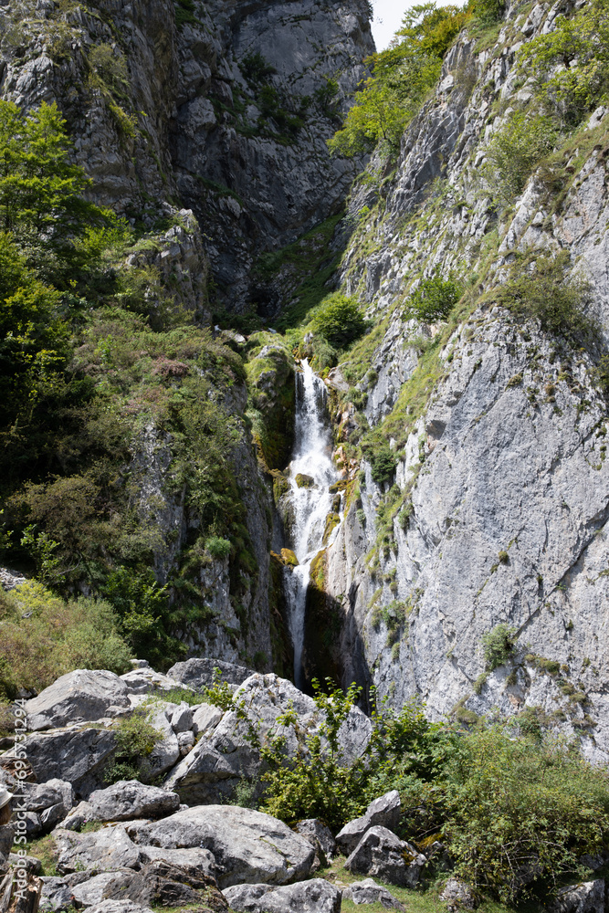 natural mountain waterfall between grey rock stone and cliff vegetation natural mountain waterfall between grey rock stone and cliff vegetation