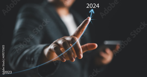 Businessman hand drawing line for increasing arrow from 2023 to 2024 for preparation merry Christmas and happy new year concept. new business, start up on new years. photo
