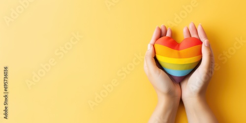 Two hands forming a heart shape in front of a vibrant rainbow flag. This image symbolizes love and support for the LGBT