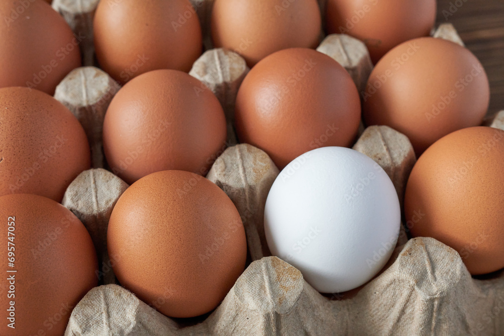 Eggs in a cardboard box. Close-up.
A white egg among brown eggs.