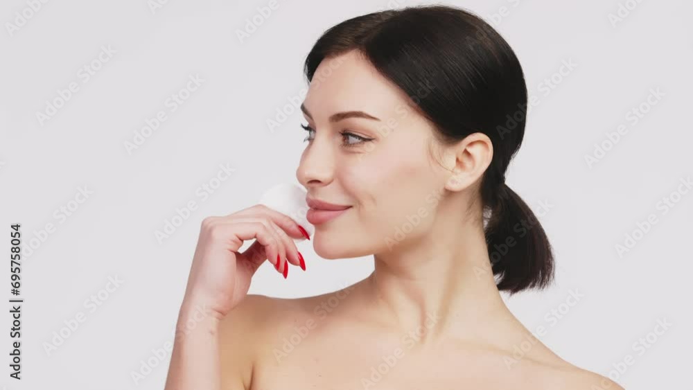 A beautiful young Caucasian woman with brown hair uses a cotton pad. The concept of advertising facial care, cosmetic natural products. A beautiful young Caucasian woman with brown hair uses a cotton pad. The concept of advertising facial care, cosmetic natural products.
