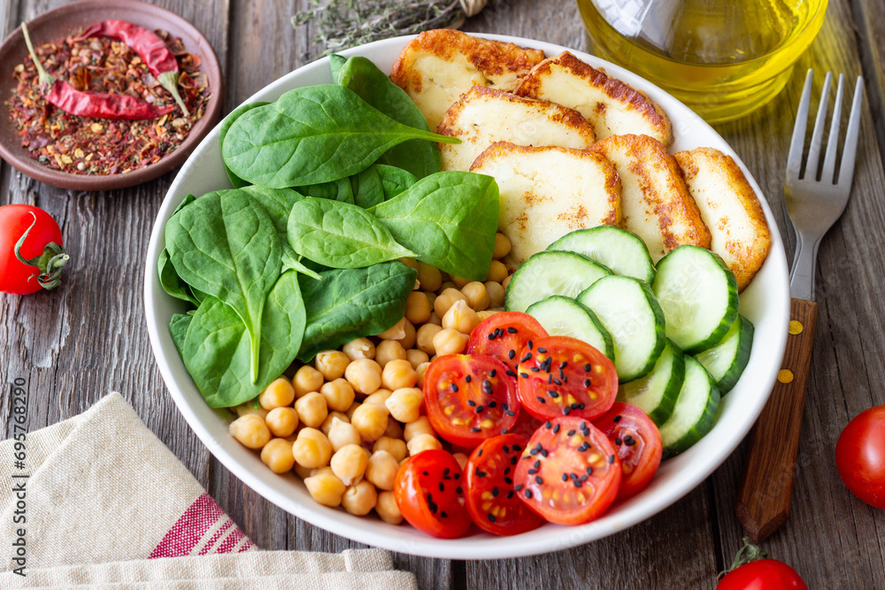 Bowl with grilled Halloumi cheese, spinach, chickpeas, tomatoes and cucumbers. Healthy eating. Vegetarian food. Diet. Bowl with grilled Halloumi cheese, spinach, chickpeas, tomatoes and cucumbers. Healthy eating. Vegetarian food. Diet.