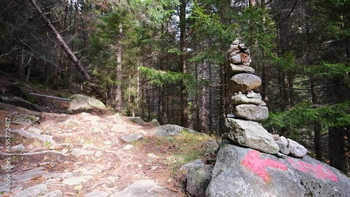 Stacked stones in the Bagni di Masino forest, arrow on a rock to indicate the direction along the path to the Onio refuge in the Oro Valley, Val Masino.