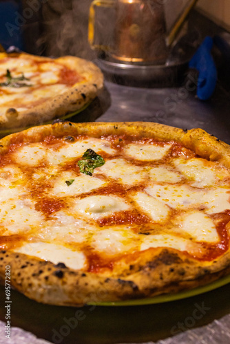 Due Pizze Margherita tradizionali napoletane condite con sugo di pomodoro, mozzarella di bufala e basilico fresco appena sfornate e pronte per essere servite
