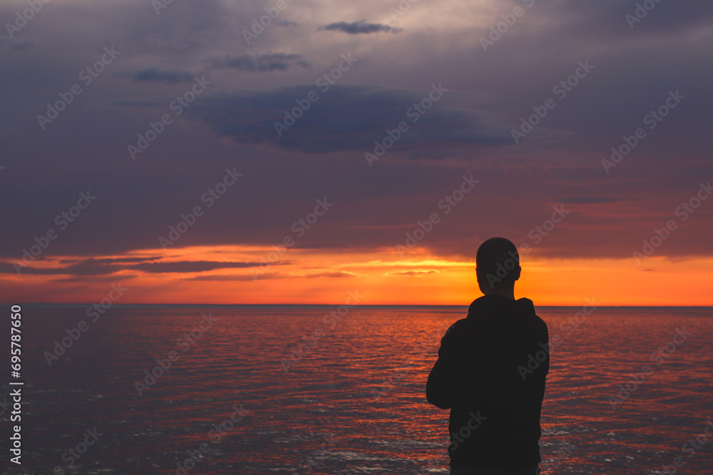 Silhouette of a man looking at the sunset on the embankment of the Black Sea coast in Kobuleti, loading.