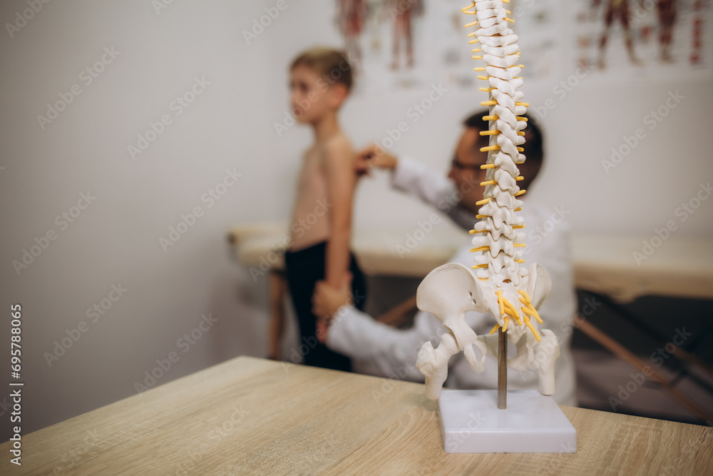 A pediatric neurologist doctor examines the back of a 5-year-old boy who has back pain. Treatment of muscle pain and scoliosis in children - obrazy, fototapety, plakaty 