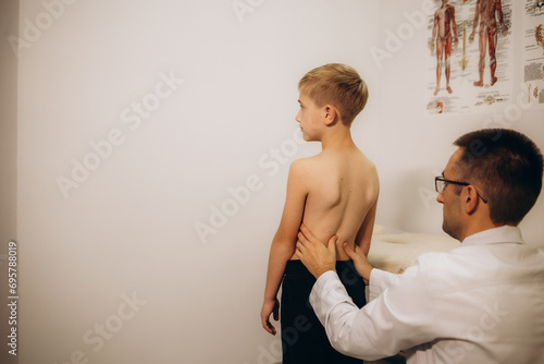 Orthopedist examining child's back in clinic. Scoliosis treatment photo