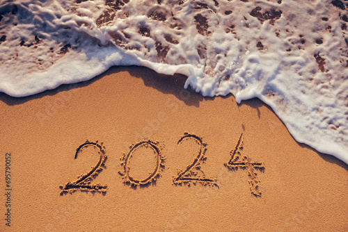 Fototapeta Naklejka Na Ścianę i Meble -  Happy New Year 2024 concept, lettering on the beach. Written text on the sea beach at sunrise.