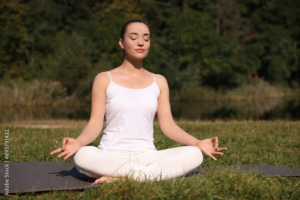 Beautiful woman practicing yoga on mat outdoors. Lotus pose Beautiful woman practicing yoga on mat outdoors. Lotus pose