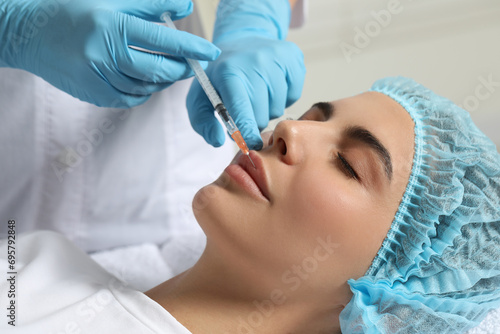 Doctor giving lips injection to young woman in clinic. Cosmetic surgery
