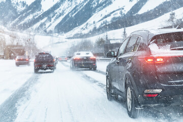 Scenic view snow covered city highway slippery mountain alpine road drive cars moving fast speed motion. Snowfall danger blizzard bad winter weather conditions. Cold snowy day snowstorm background