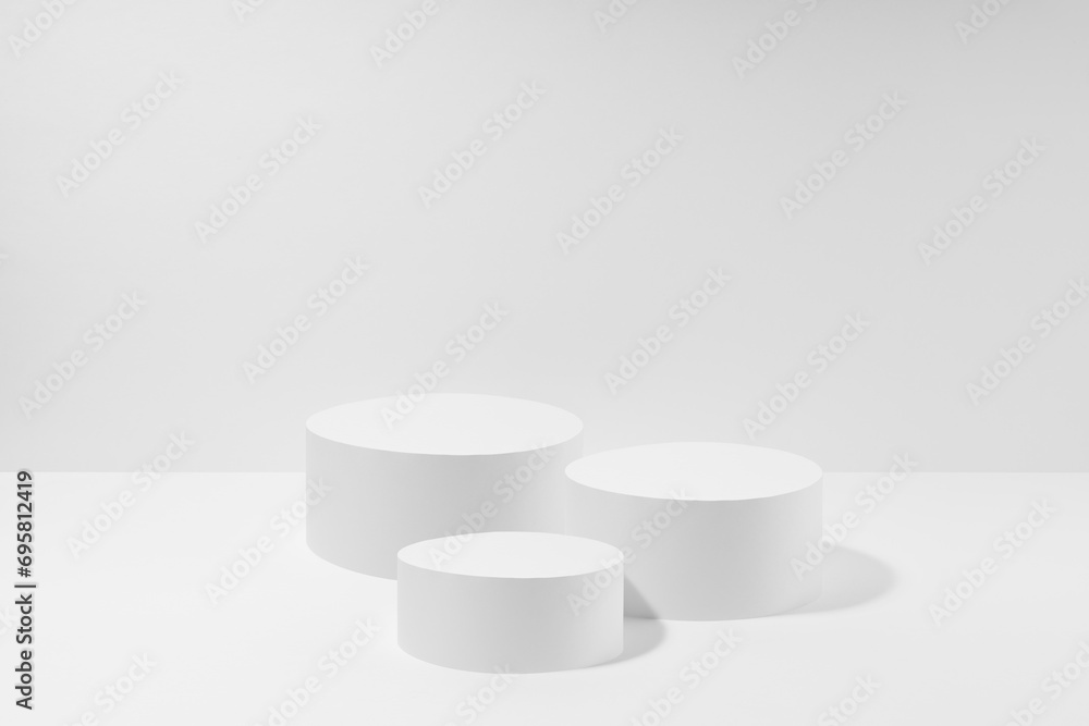Abstract set of three white round podiums for cosmetic products, mockup on white background. White stage template in elegant simplicity style for showing products, advertising, design, poster, text. Abstract set of three white round podiums for cosmetic products, mockup on white background. White stage template in elegant simplicity style for showing products, advertising, design, poster, text.