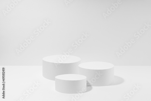 Abstract set of three white round podiums for cosmetic products, mockup on white background. White stage template in elegant simplicity style for showing products, advertising, design, poster, text.
