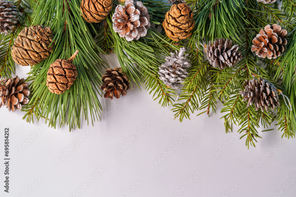 Fototapeta premium A Christmas composition. A frame of pine and fir branches and fir cones and Christmas balls and decorations on a white background. Flat layout, top view, copy space