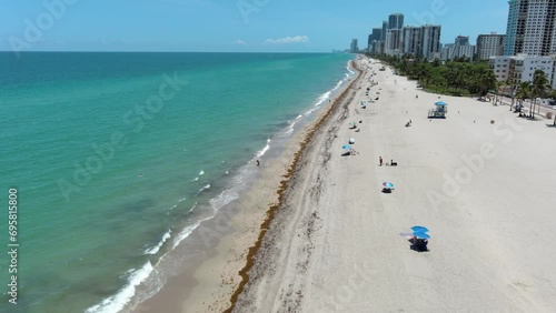 Over the seashore, beach, waves, sun, blue sky, white clouds. Filming from a drone.