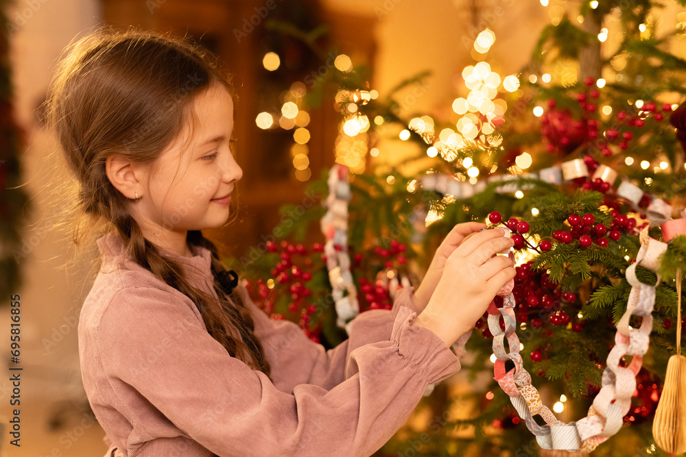 girl with braids decorates Christmas tree with flashing lights by garlands at home during holidays girl with braids decorates Christmas tree with flashing lights by garlands at home during holidays