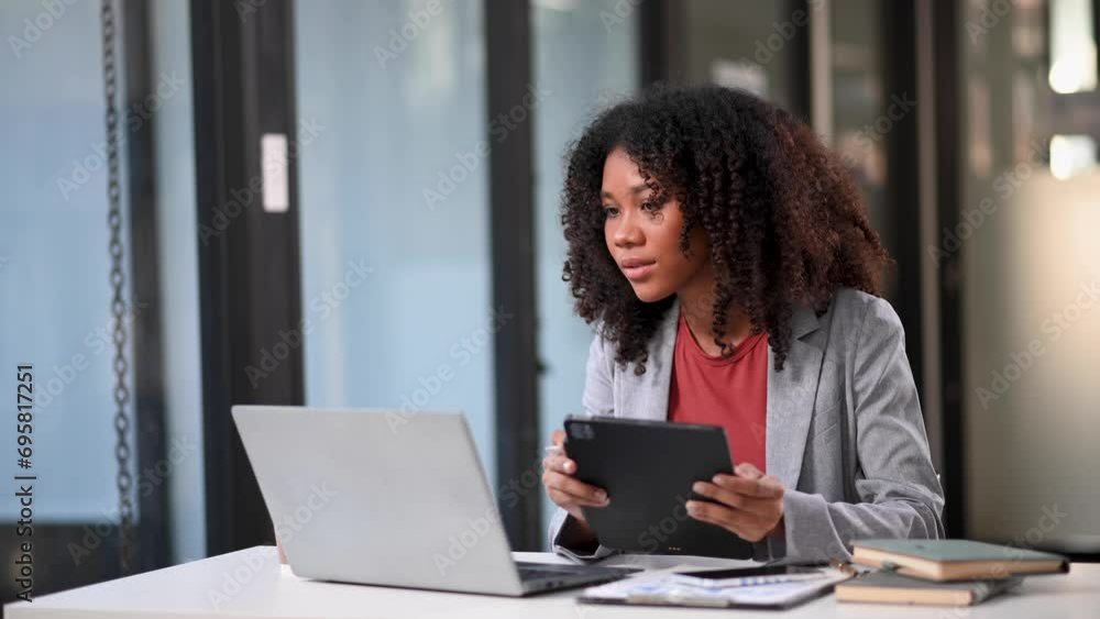 Young beautiful woman typing on tablet and laptop while sitting at the working white table Young beautiful woman typing on tablet and laptop while sitting at the working white table