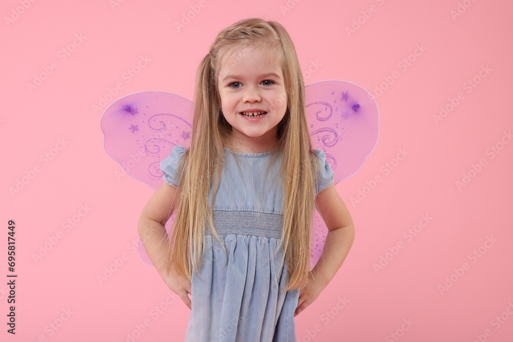Cute little girl in fairy costume with violet wings on pink background Cute little girl in fairy costume with violet wings on pink background