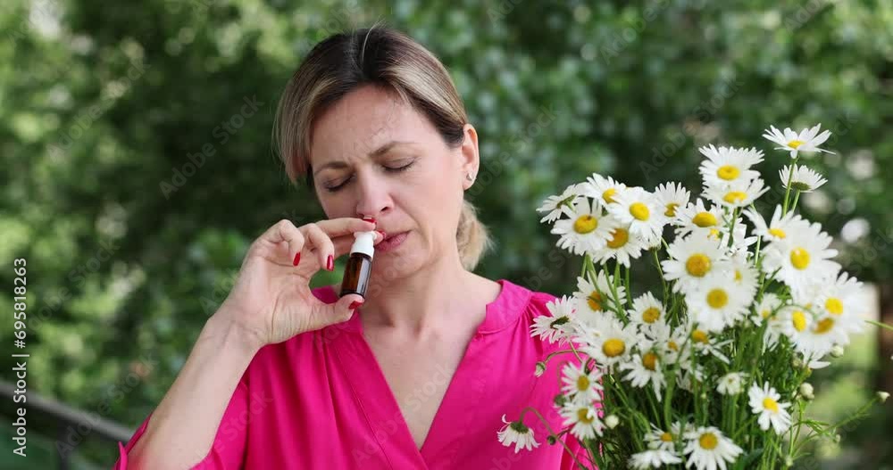 Sick dissatisfied woman sprays nasal medicine walking in blooming spring garden and holding chamomile flowers. Antiallergic and symptomatic treatment of rhinitis Sick dissatisfied woman sprays nasal medicine walking in blooming spring garden and holding chamomile flowers. Antiallergic and symptomatic treatment of rhinitis
