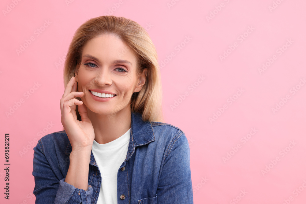 Portrait of smiling middle aged woman with blonde hair on pink background. Space for text Portrait of smiling middle aged woman with blonde hair on pink background. Space for text