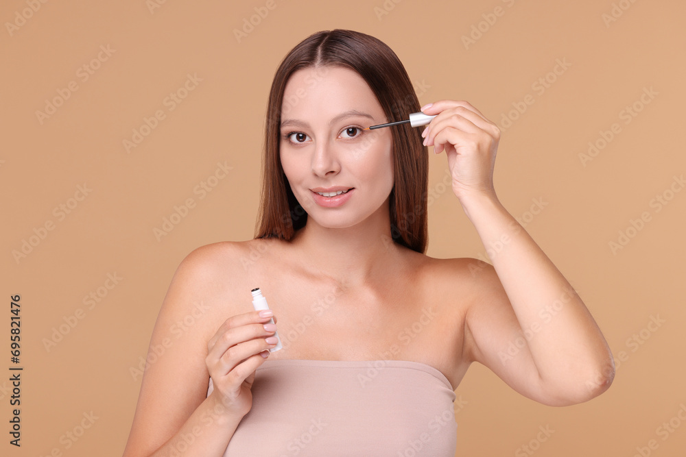 Beautiful woman applying serum onto eyelashes on beige background Beautiful woman applying serum onto eyelashes on beige background