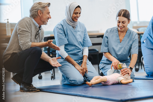 Female nursing students using infant CPR simulator in medical paediatric training photo