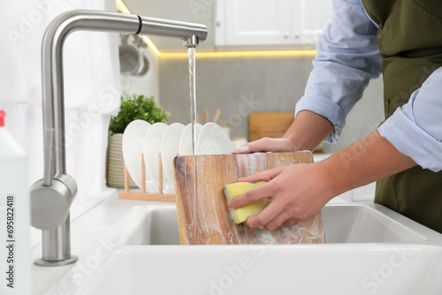 Bild auf Leinwand Man washing wooden cutting board in kitchen sink, closeup