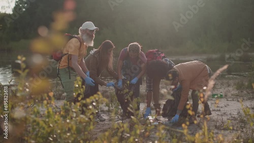 teamwork of multiethnic volunteers cleaning plastic riverbank - Activists collecting trash and plastic in nature for a greener planet