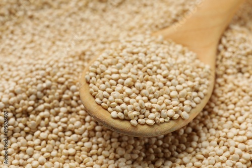 Wooden spoon and raw quinoa as background, closeup