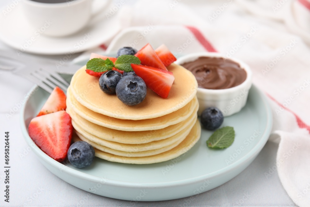 Delicious pancakes with strawberries, blueberries and chocolate sauce on light table, closeup Delicious pancakes with strawberries, blueberries and chocolate sauce on light table, closeup