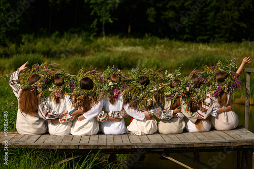 Girls in woven wreaths of different flowers and grass on a warm summer day. photo