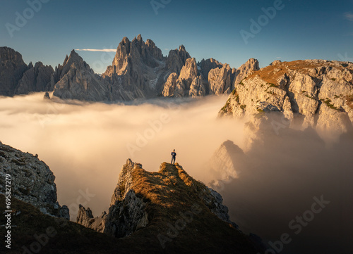 Majestic Sunrise Over Tre Cime Dolomites: Aerial View of Mountain Peaks in Tranquil Cloud Inversion (ID: 695827279)