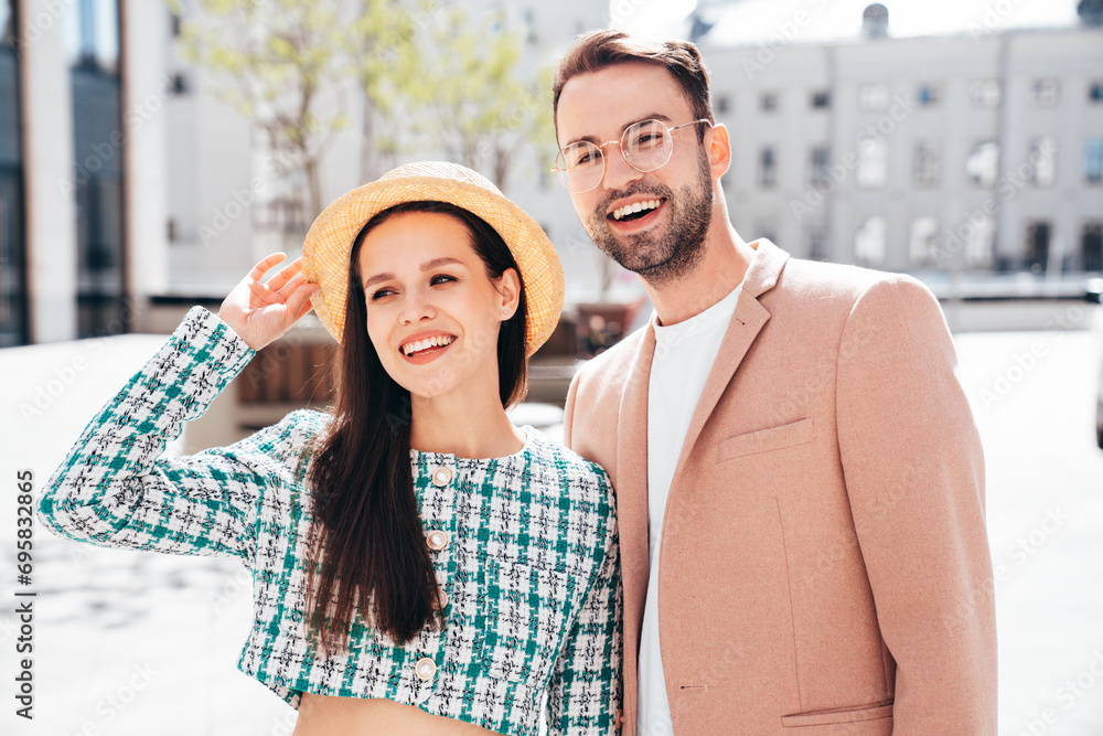 Naklejka premium Beautiful fashion woman and her handsome elegant boyfriend in beige suit. Sexy brunette model in summer clothes. Fashionable smiling couple posing in street Europe. Brutal man and female outdoors