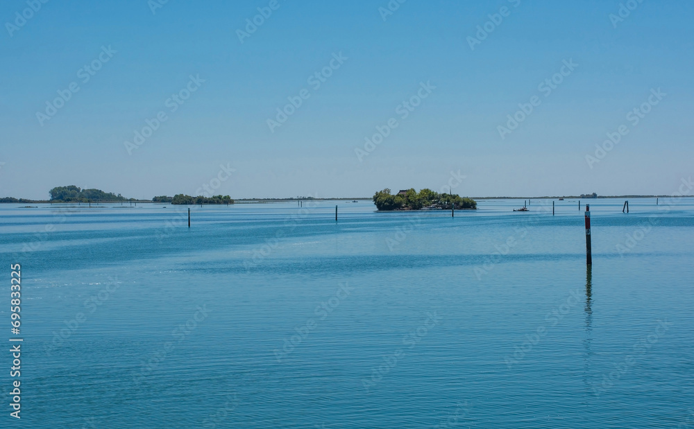 Markers show the edge of a navigable channel in the shallow waters in the Grado section of the Marano and Grado Lagoon in Friuli-Venezia Giulia, north east Italy. August