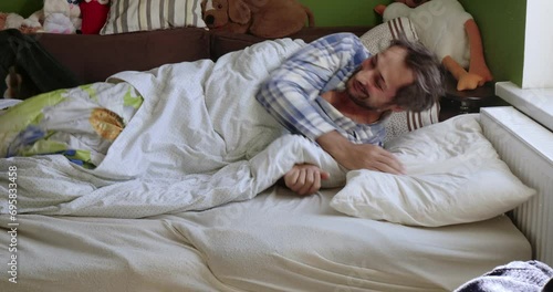 A border collie puppy runs on a bed where a man sleeps. The man wakes up and laughs, and the dog looks out the window.