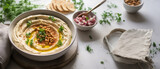 Homemade creamy hummus in bowl on gray table background, top view