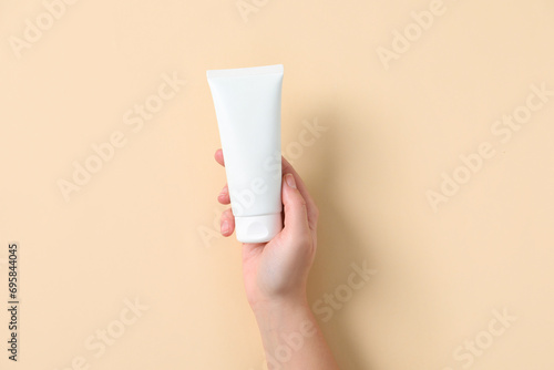 Woman with tube of hand cream on beige background, top view © New Africa